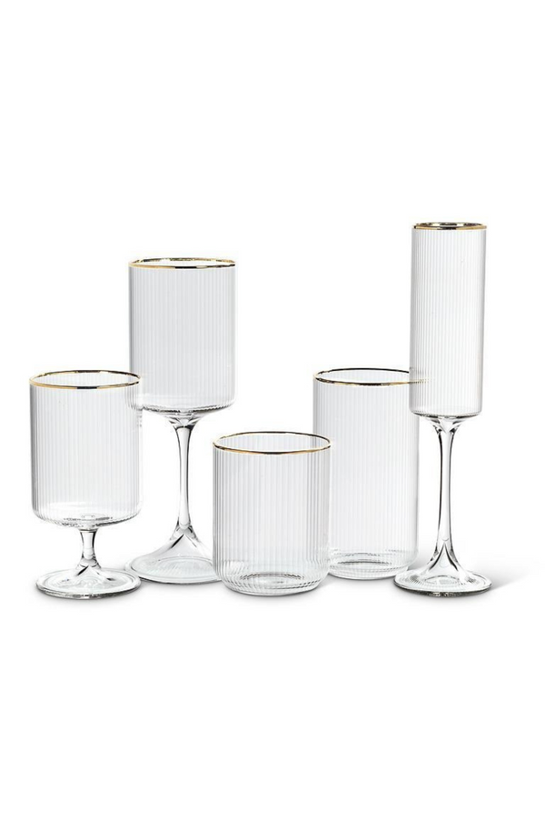 Set of clear ribbed glassware with gold rims on a white background
