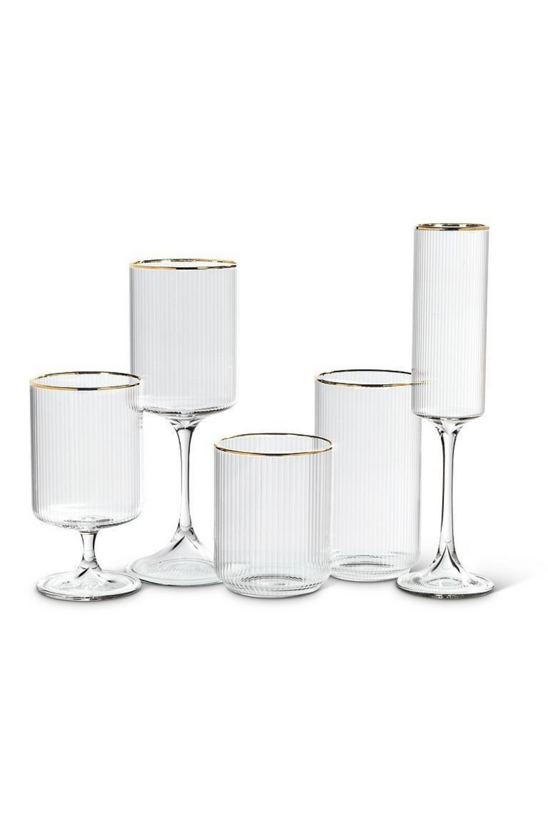 Set of clear ribbed glassware with gold rims on a white background