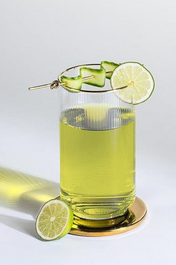 Glass of green drink with lime slices on a white background
