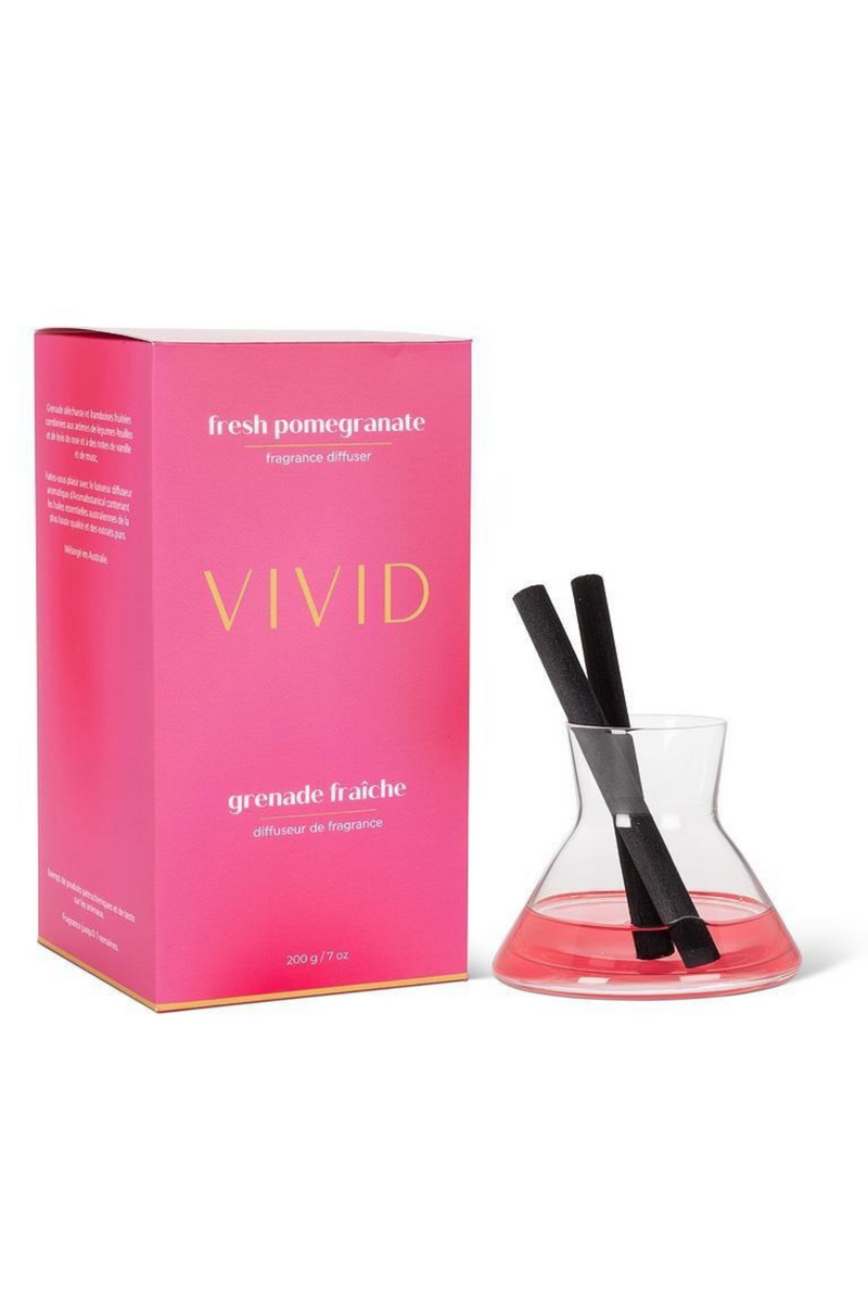 Vivid fresh pomegranate diffuser set with pink box and glass bottle on a white background