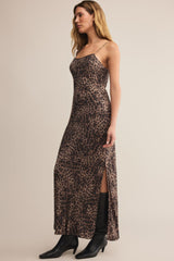 Woman wearing a leopard print dress with black boots on a beige background