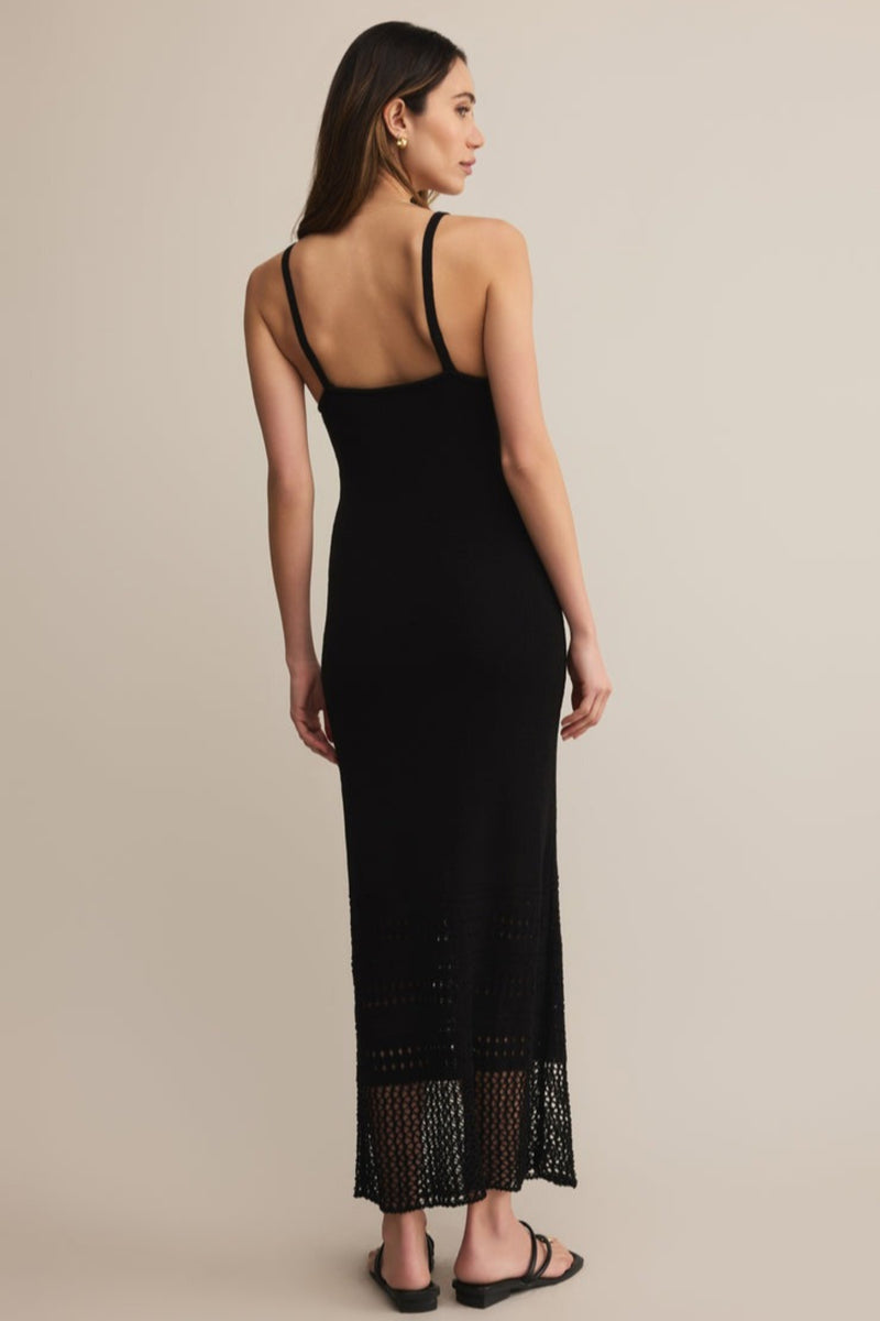 Woman wearing a black dress with lace hem on a beige background