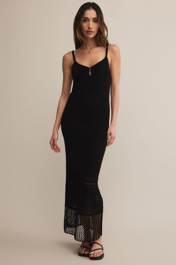 Woman wearing a black dress with lace details on a beige background