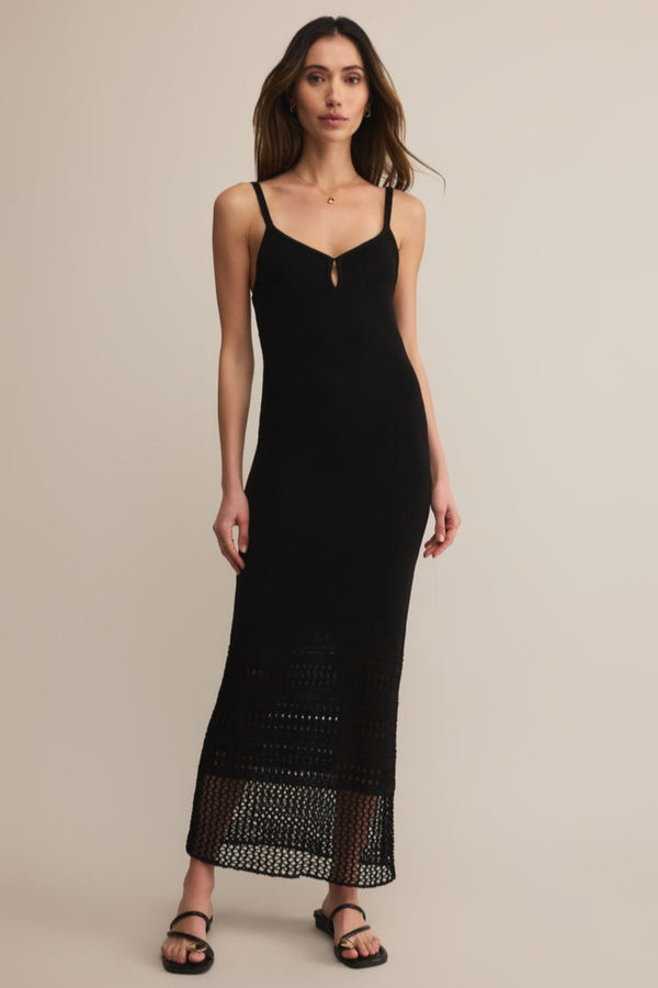 Woman wearing a black slip dress with lace hem on a beige background