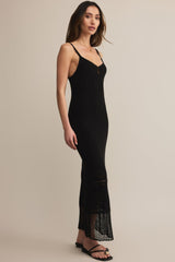 Woman wearing a black dress with lace details on a beige background