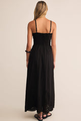 Woman wearing a black dress with thin straps on a beige background