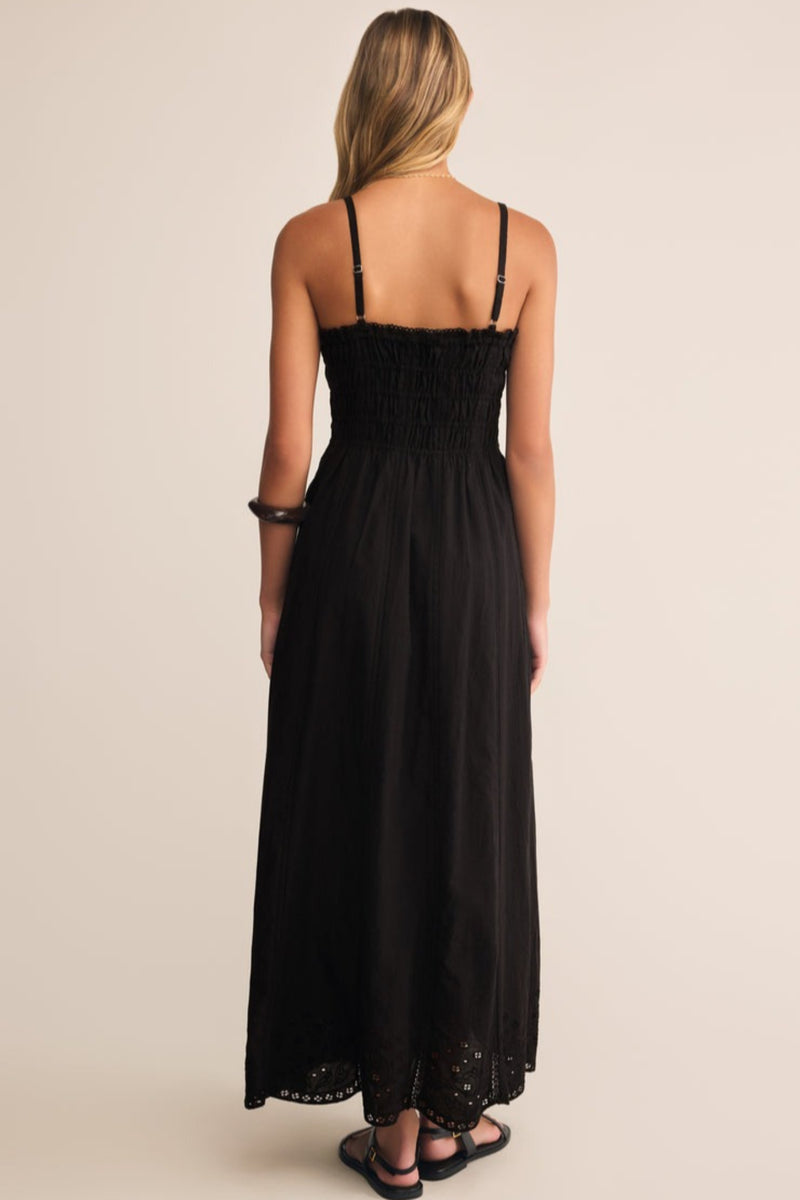 Woman wearing a black dress with thin straps on a beige background