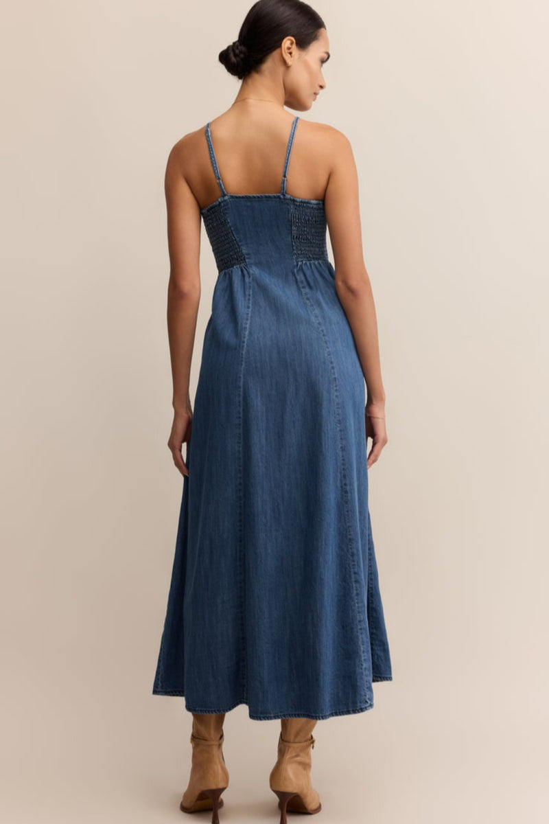 Woman wearing a blue denim dress against a beige background