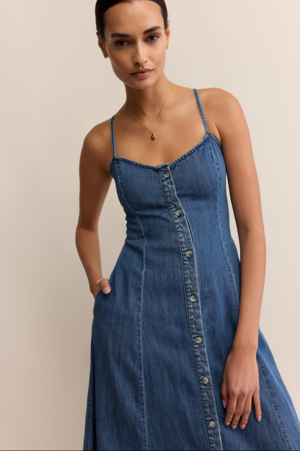 Woman wearing a blue denim dress against a beige background