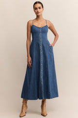 Woman wearing a blue denim dress against a beige background