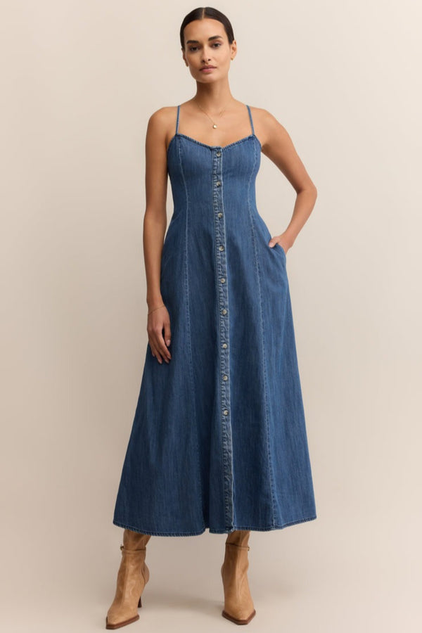 Woman wearing a blue denim dress against a beige background