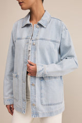 Light blue denim jacket worn by a person on a beige background