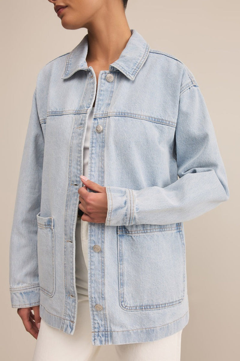 Light blue denim jacket worn by a person on a beige background