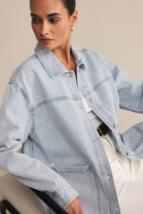 Woman wearing a light blue denim jacket against a neutral background