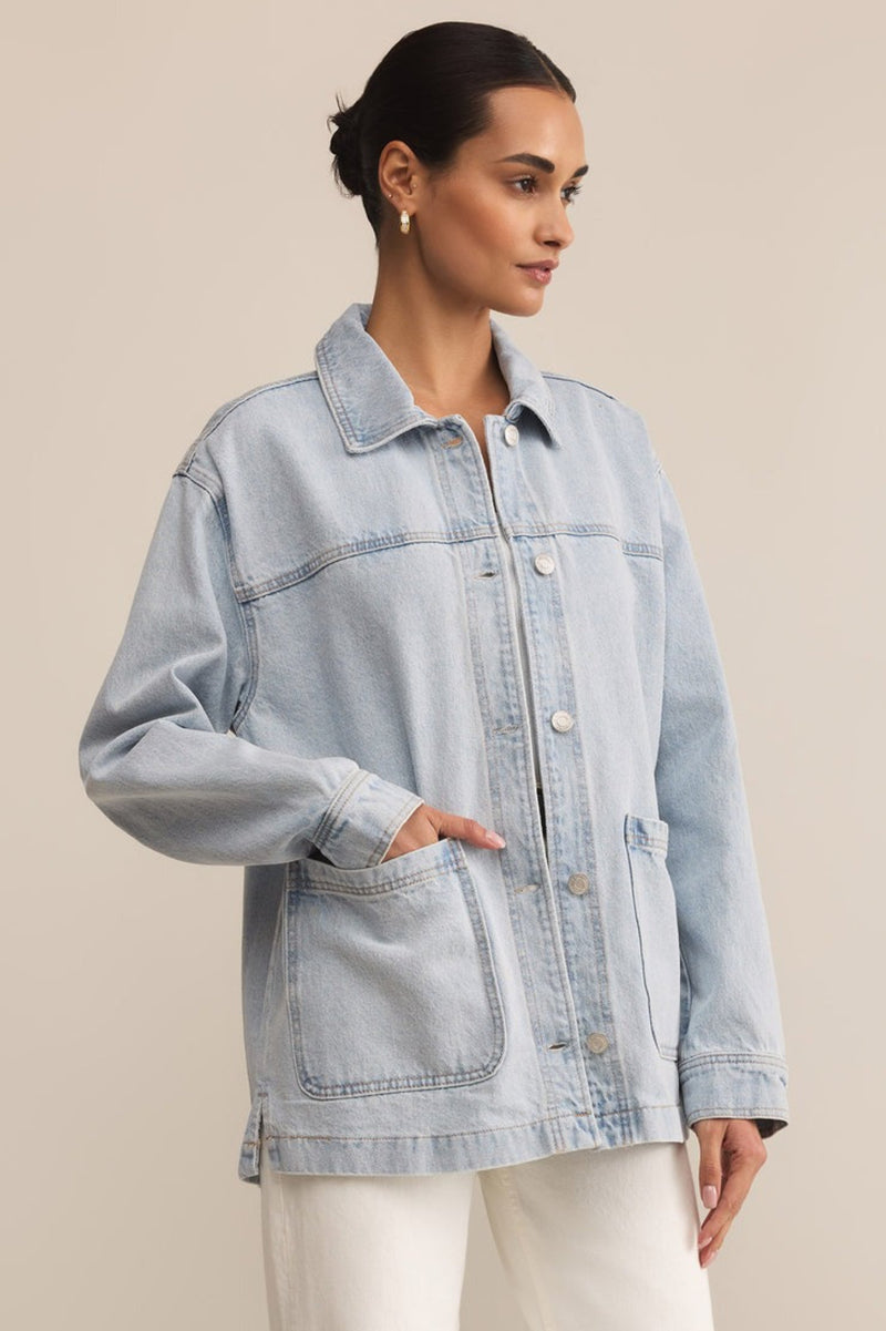 Woman wearing a light blue denim jacket against a beige background