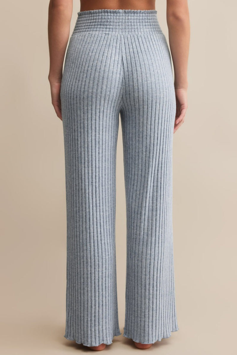 Blue ribbed pants worn by a person on a beige background