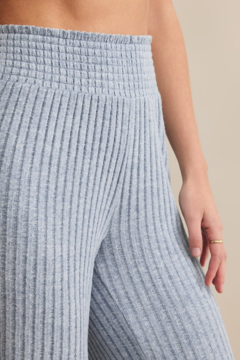 Close-up of blue ribbed knit pants on a neutral background