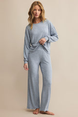 Woman wearing a blue ribbed pajama set on a beige background