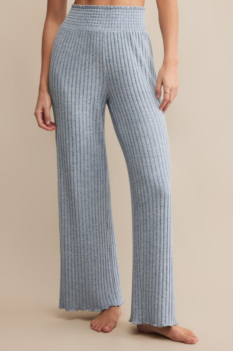 Person wearing blue ribbed lounge  pants on a beige background