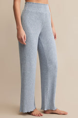 Person wearing blue ribbed pants on a beige background