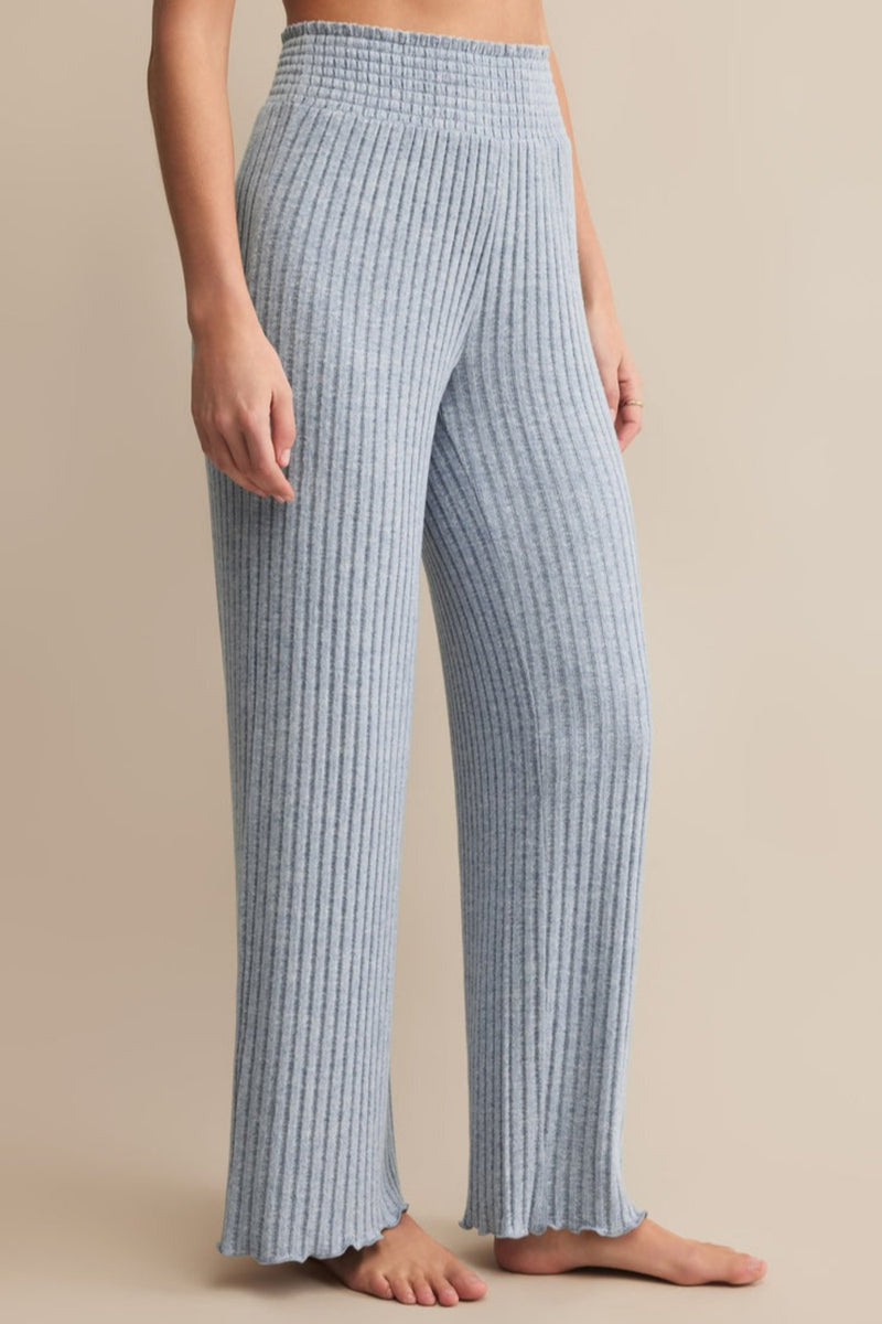 Person wearing blue ribbed pants on a beige background