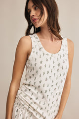 Woman wearing a white sleeveless dress with floral pattern against a neutral background