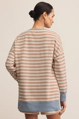 Woman wearing a striped sweater and shorts on a beige background