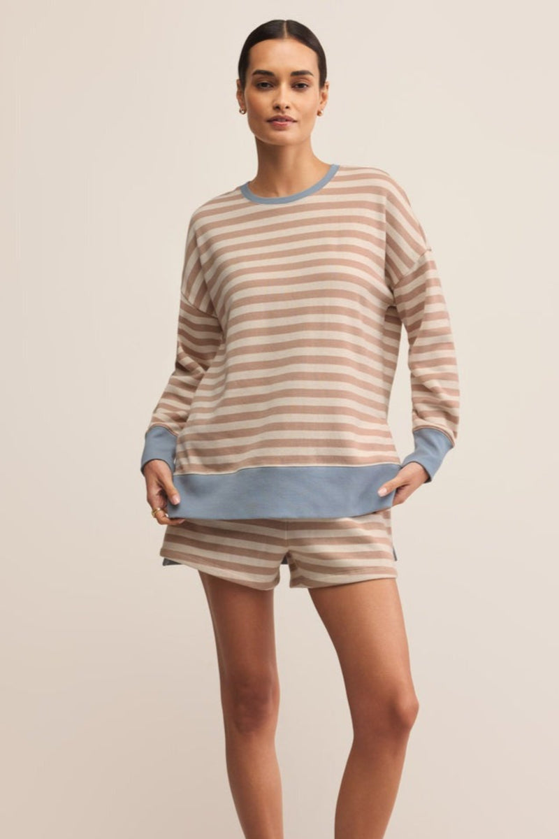 Woman wearing a striped sweater and shorts on a beige background