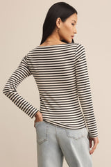 Woman wearing a black and white striped long-sleeve top with light blue jeans on a beige background