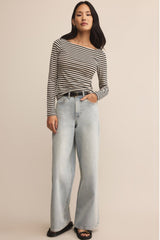 Woman wearing a striped shirt and light blue jeans on a beige background
