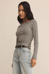 Woman wearing a black and white striped long-sleeve top and light blue jeans on a beige background