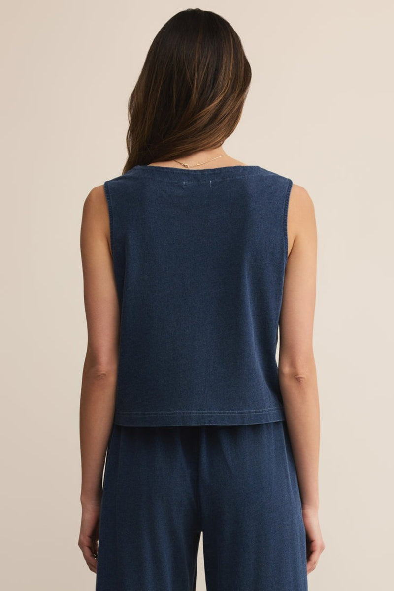 Woman wearing a sleeveless navy top and pants on a beige background