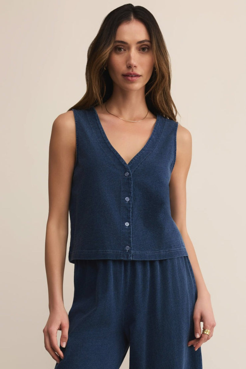 Woman wearing a blue sleeveless top and pants on a beige background
