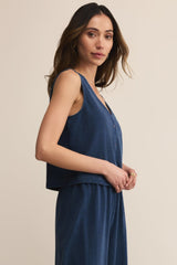 Woman wearing a blue sleeveless top and skirt set against a beige background
