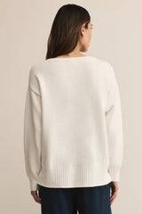 Person wearing a white sweater on a beige background