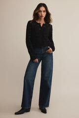 Woman wearing a black top and blue jeans on a beige background