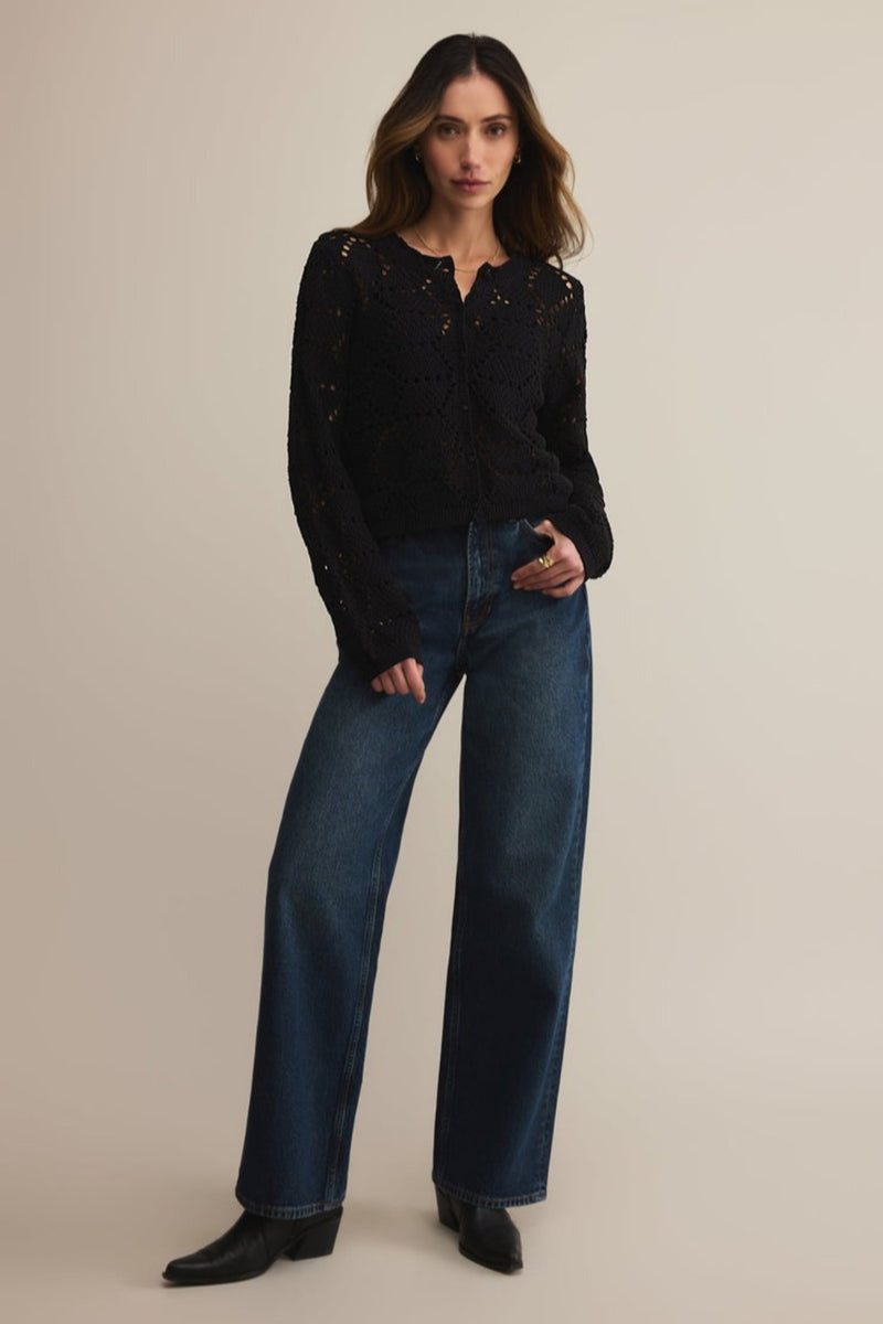 Woman wearing a black top and blue jeans on a beige background