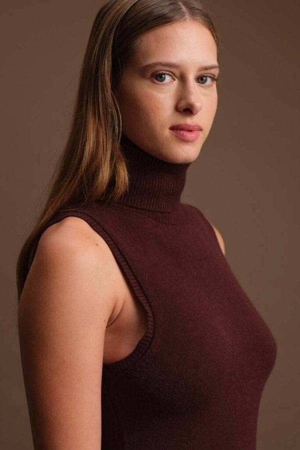 Woman wearing a brown sleeveless turtleneck against a brown background