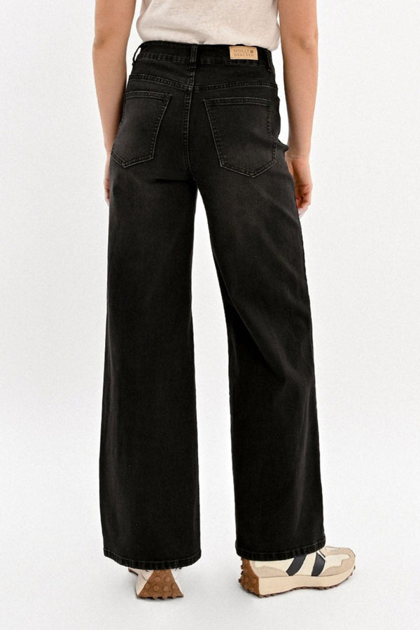 Person wearing black wide-leg jeans on a white background