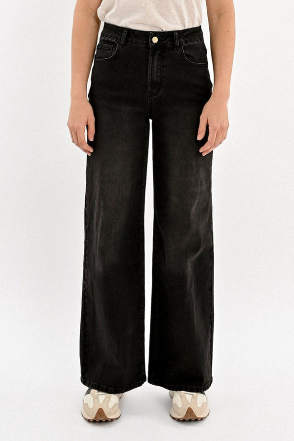 Person wearing black wide-leg jeans on a white background