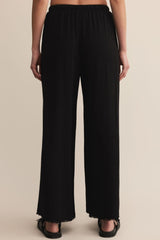 Black wide-leg pants worn by a person on a beige background
