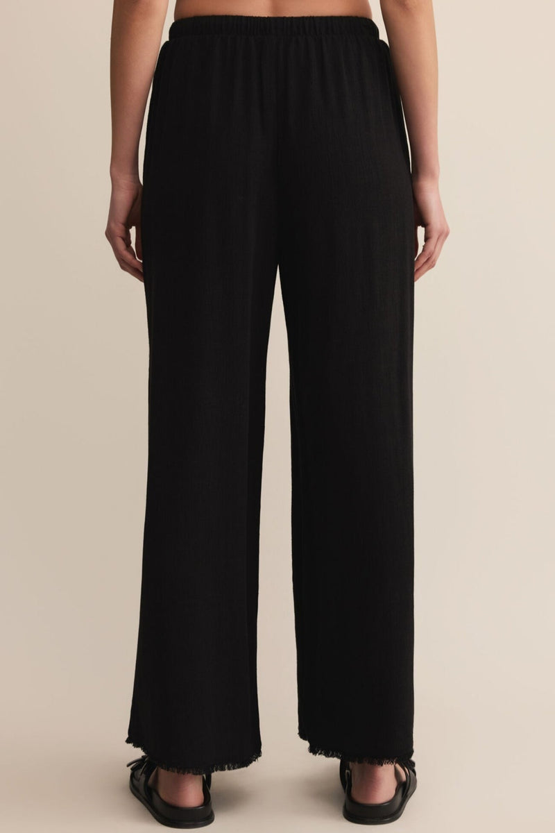 Black wide-leg pants worn by a person on a beige background