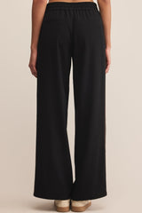 Black wide-leg pants worn by a person on a beige background