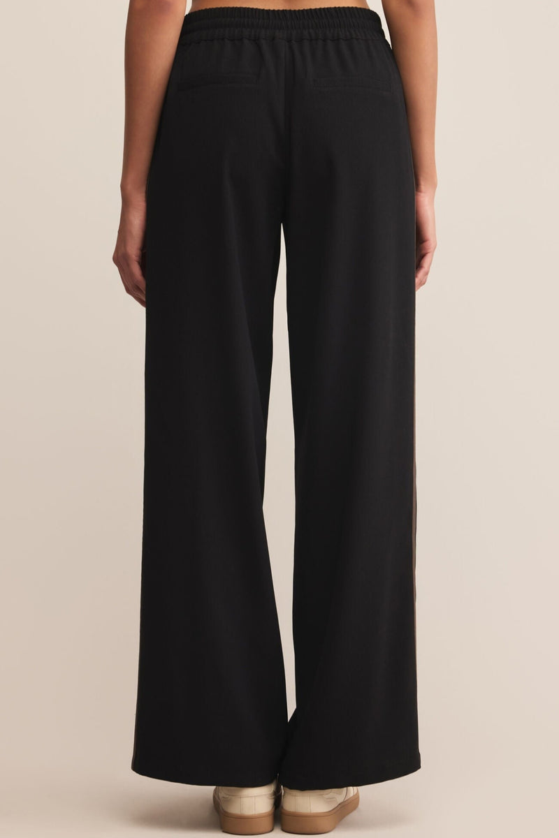 Black wide-leg pants worn by a person on a beige background