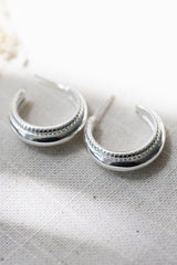 Silver hoop earrings on a textured white surface