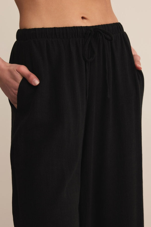 Black pants worn by a person on a beige background