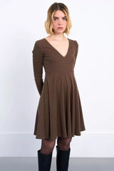 Woman wearing a brown dress with long sleeves on a white background
