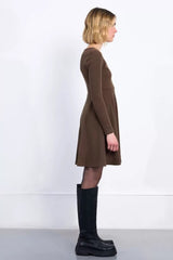 Woman wearing a brown dress and black boots against a white background