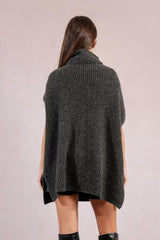 Person wearing a dark gray knitted poncho against a light background