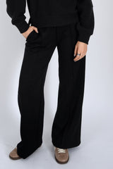 Person wearing black pants and a black top on a white background